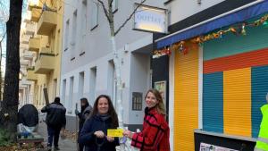 Zwei Personen pflanzen einen Baum vor einem Wohnhaus