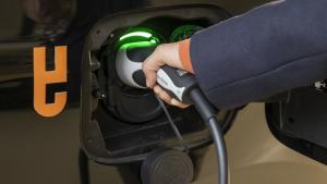 Eine Person steckt ein Ladekabel in ein mit dem BEA-Logo versehenes E-Auto.